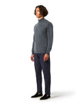 Man wearing a gray sweater and dark pants on a white background