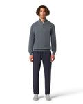Man wearing a gray sweater and dark pants on a white background
