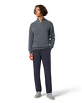 Man wearing a gray sweater and navy pants on a white background