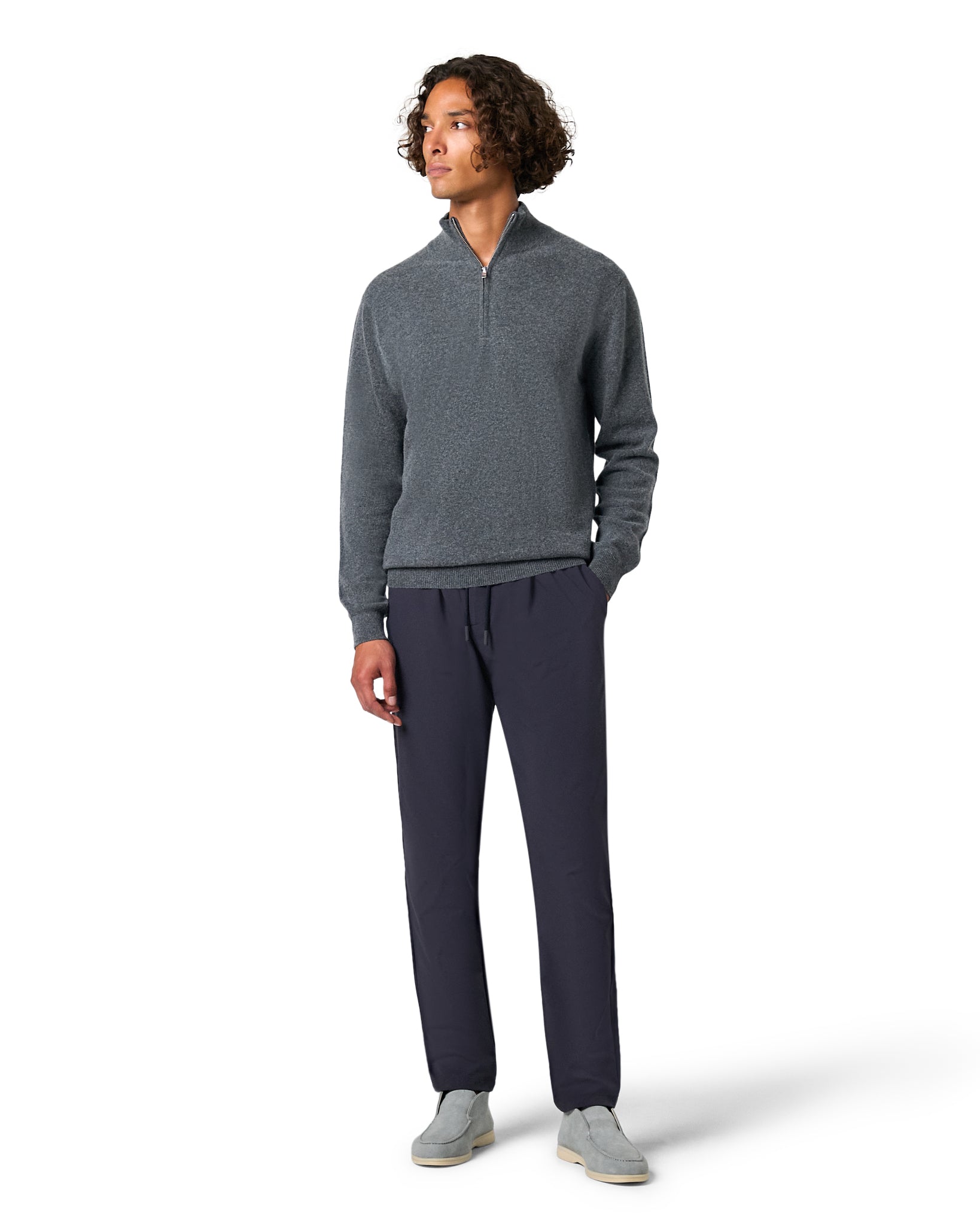 Man wearing a gray sweater and navy pants on a white background