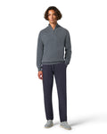 Man wearing a gray sweater and dark pants on a white background