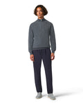 Man wearing a gray sweater and navy pants on a white background
