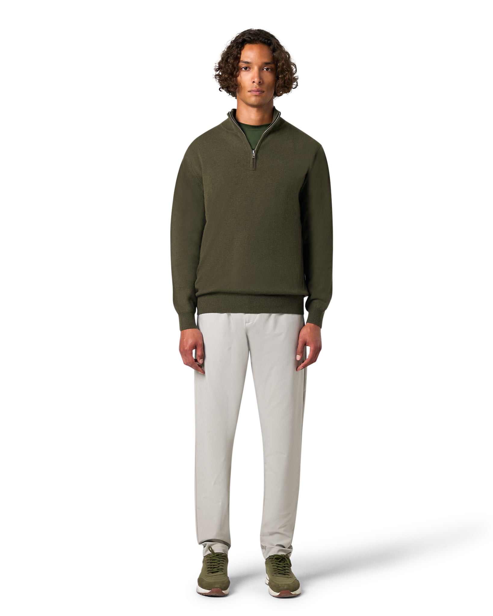 Man wearing a green sweater and white pants on a white background