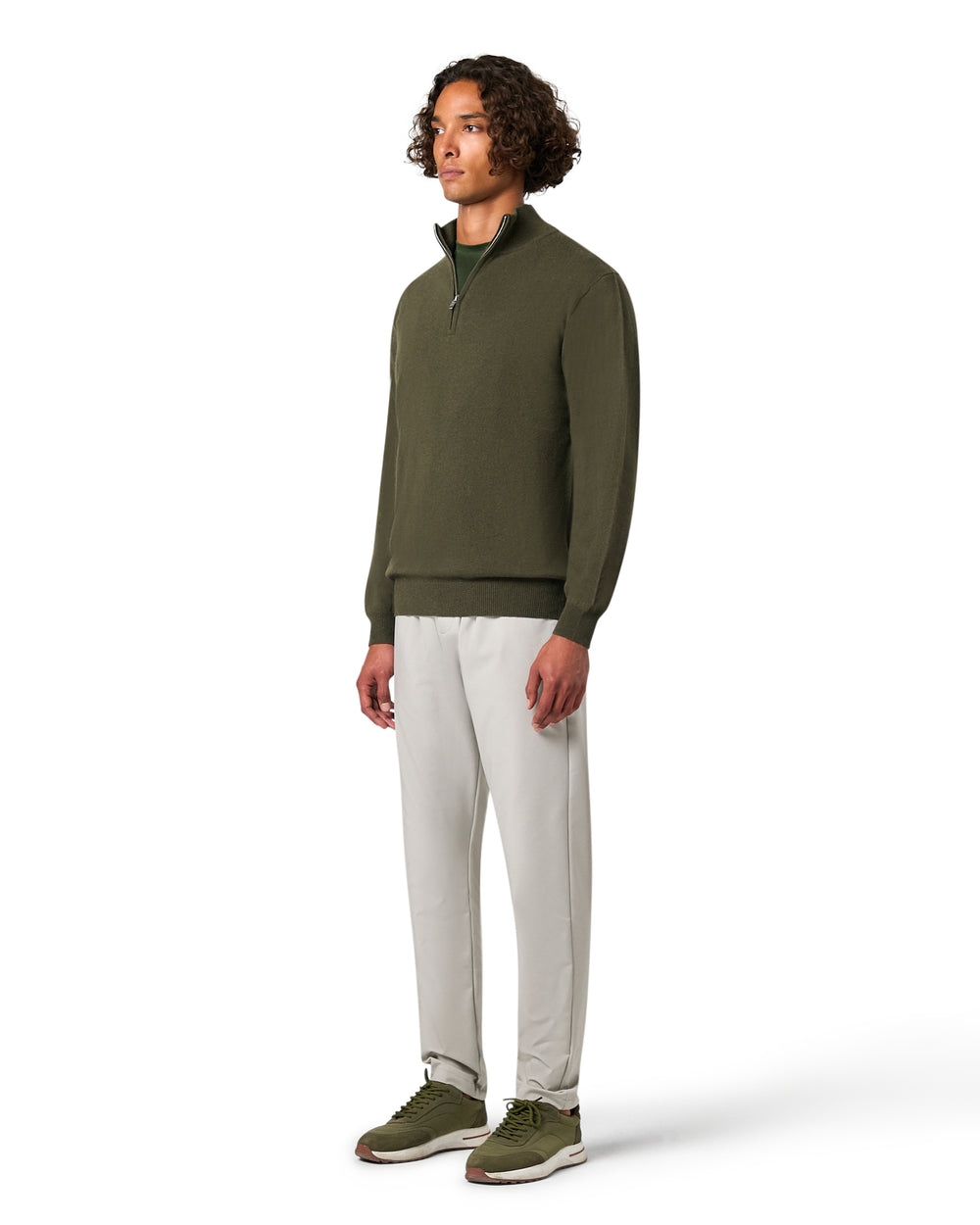 Man wearing a green sweater and white pants on a white background