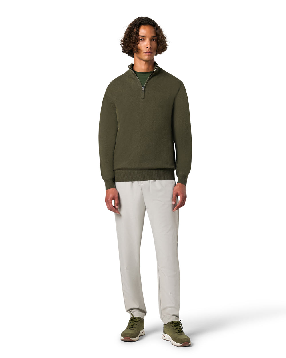 Man wearing a green sweater and beige pants on a white background