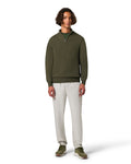 Man wearing a green sweater and beige pants on a white background