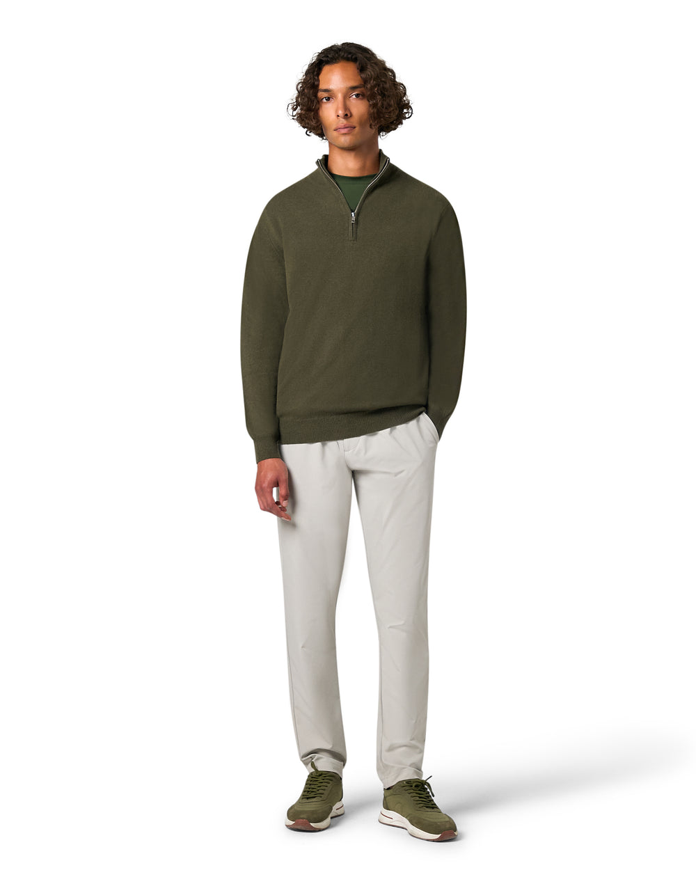Man wearing a green sweater and white pants on a white background