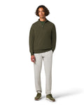 Man wearing a green sweater and white pants on a white background