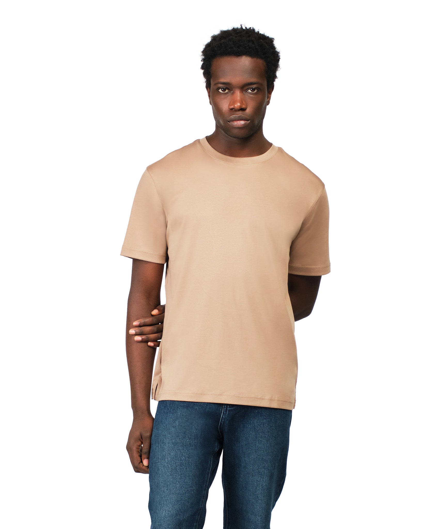 Man wearing a beige t-shirt and blue jeans on a white background