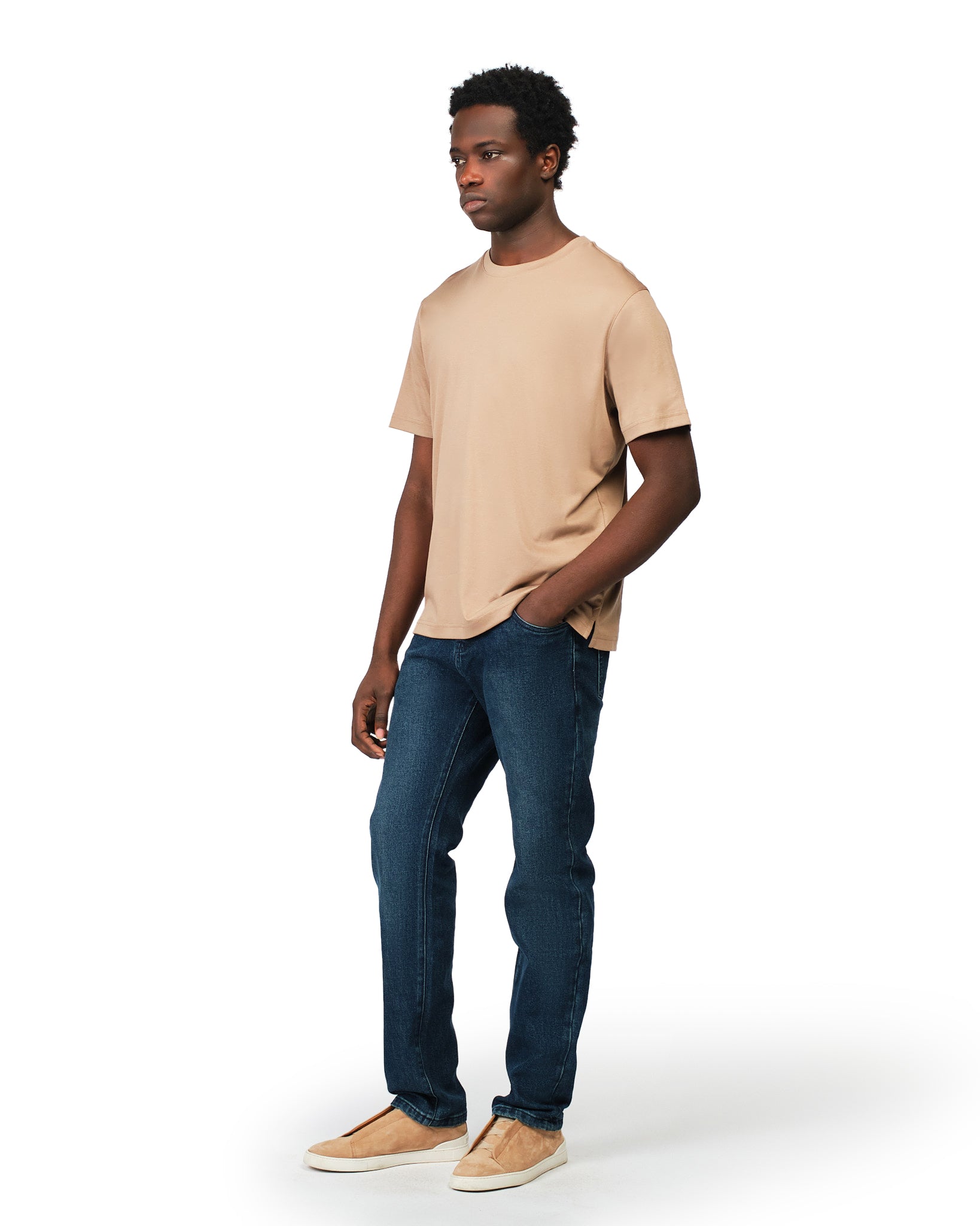 Man wearing a beige t-shirt and blue jeans on a white background