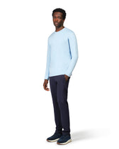 Man wearing a light blue sweater and dark pants on a white background