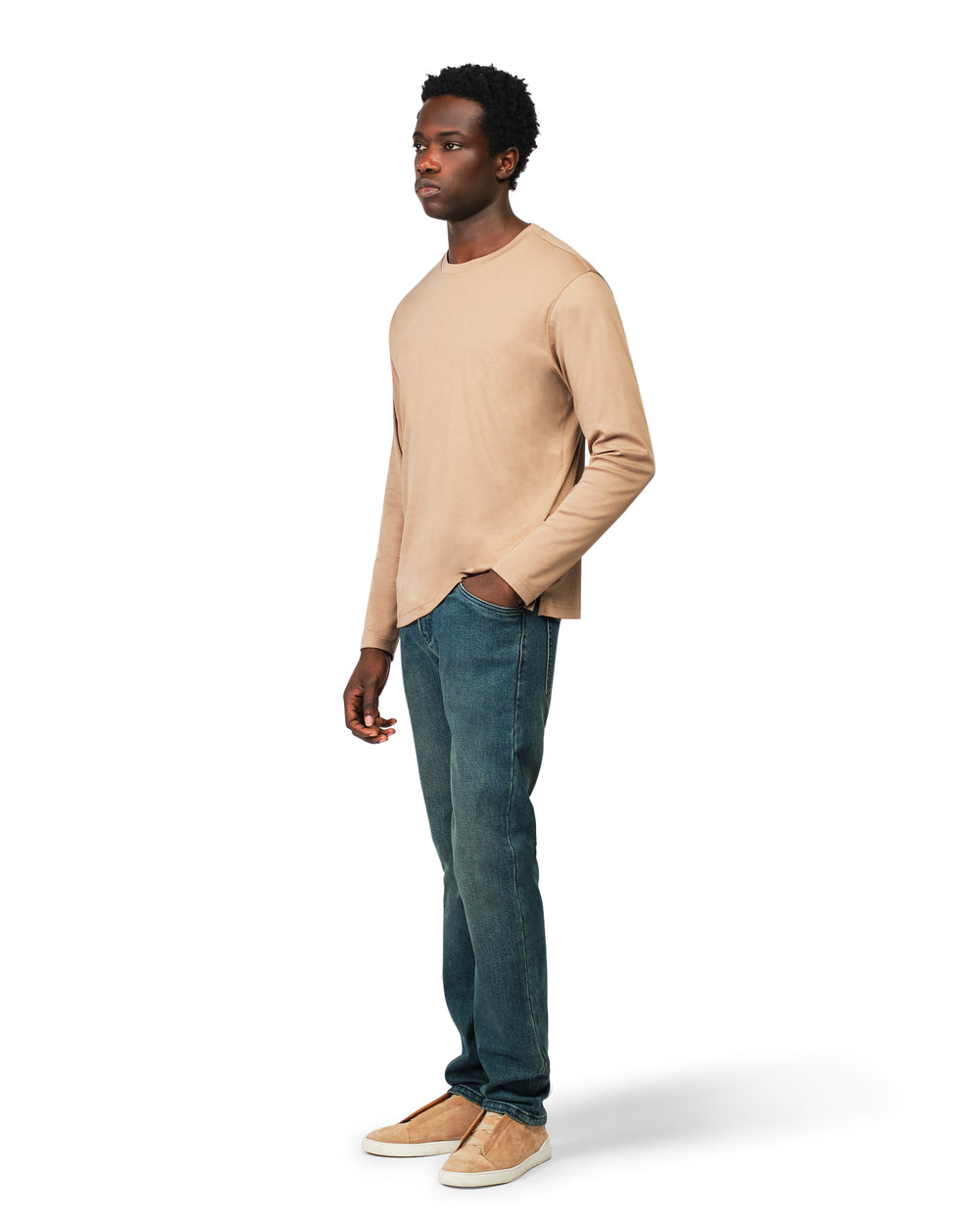 Man wearing a beige sweater and blue jeans on a white background