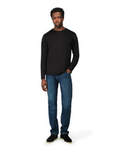 Man wearing a black long-sleeve shirt and blue jeans on a white background
