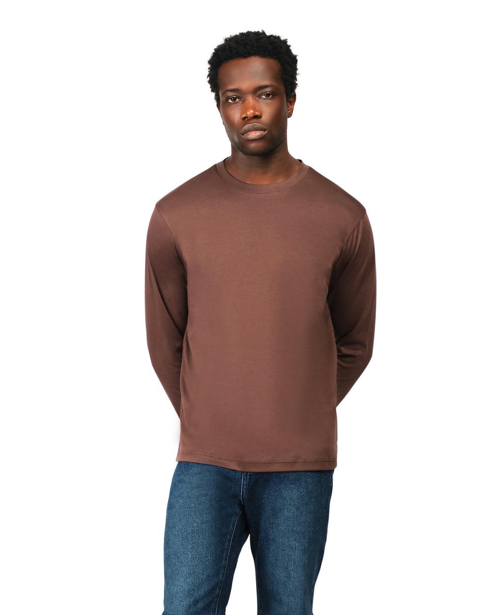 Man wearing a brown long-sleeve shirt and blue jeans on a white background