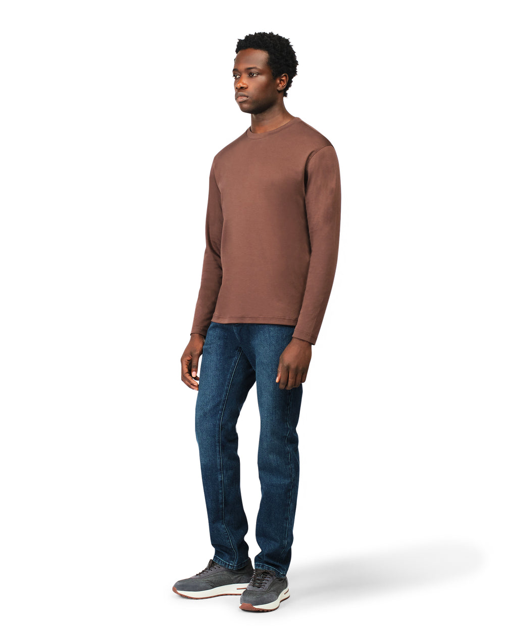 Man wearing a brown long-sleeve shirt and blue jeans on a white background