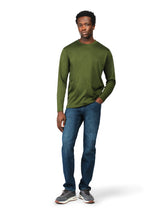 Man wearing a green long-sleeve shirt and blue jeans on a white background