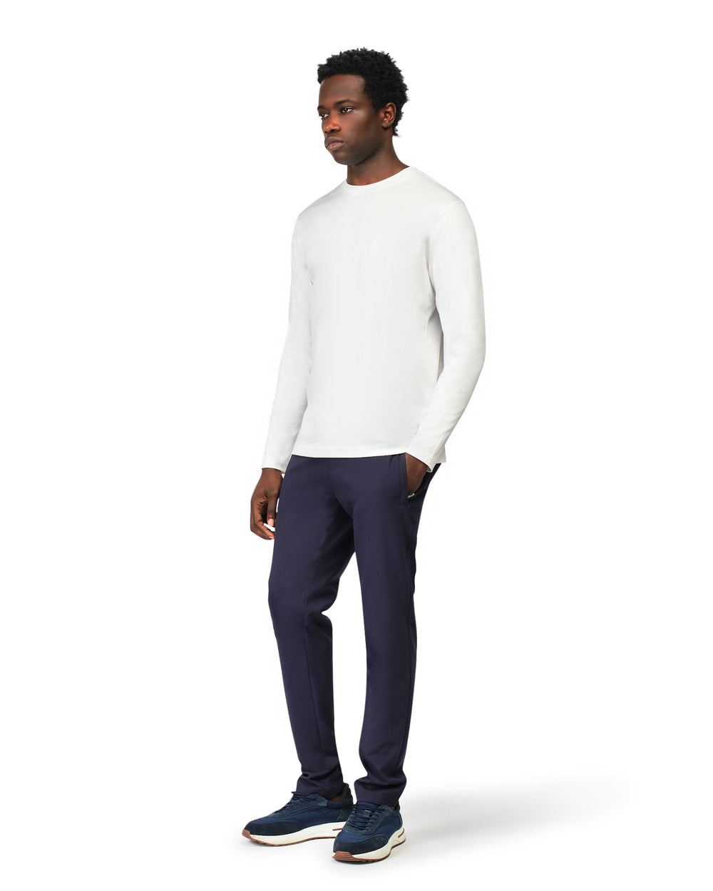 Man wearing a white long-sleeve shirt and navy pants on a white background