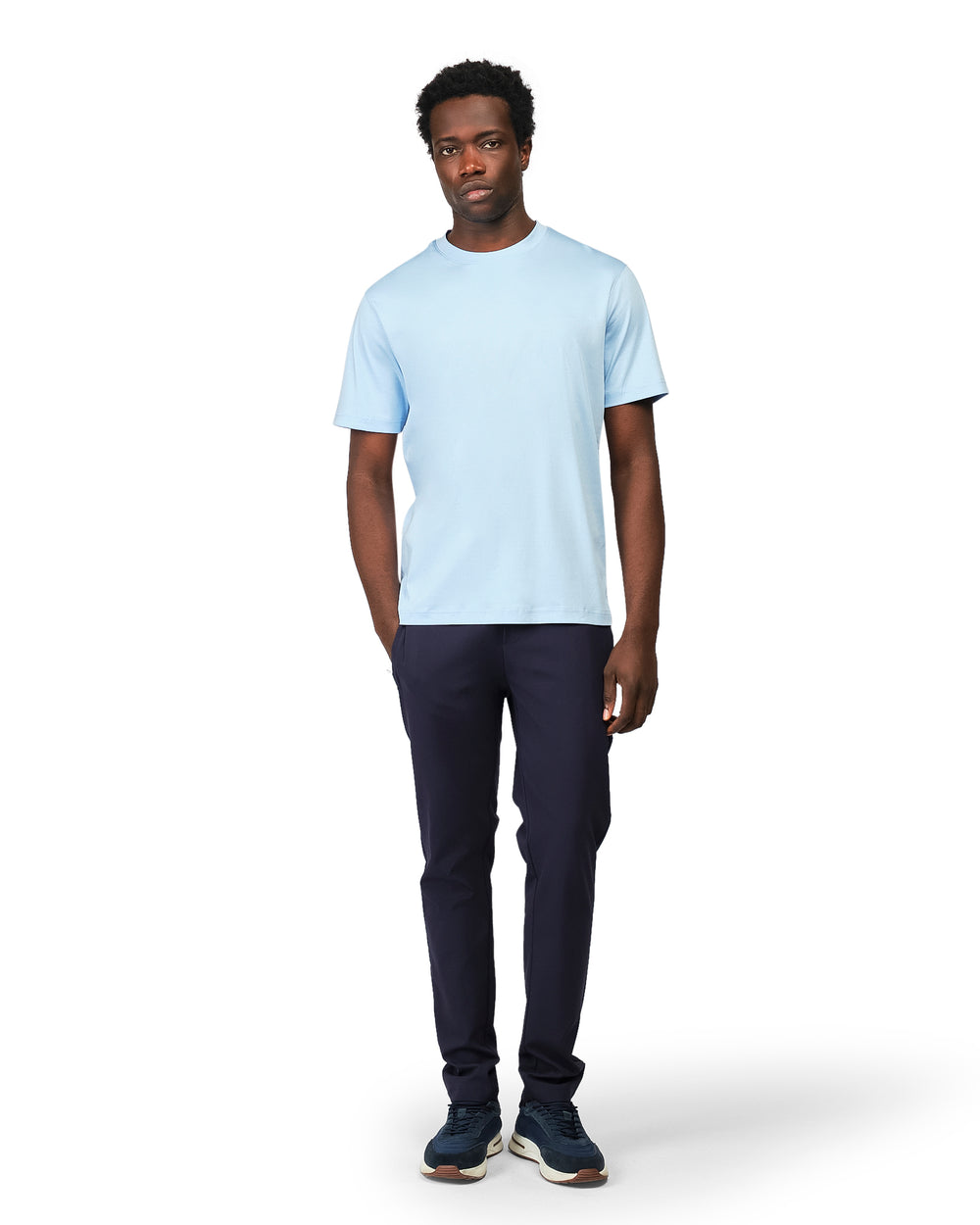 Man wearing a light blue t-shirt and dark pants on a white background