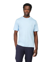 Man wearing a light blue t-shirt and dark pants on a white background
