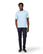 Man wearing a light blue t-shirt and dark pants on a white background