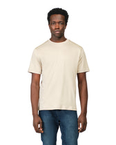 Man wearing a plain beige t-shirt and blue jeans on a white background