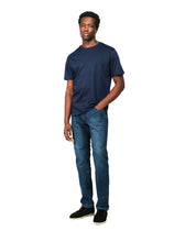 Man wearing a navy t-shirt and blue jeans on a white background