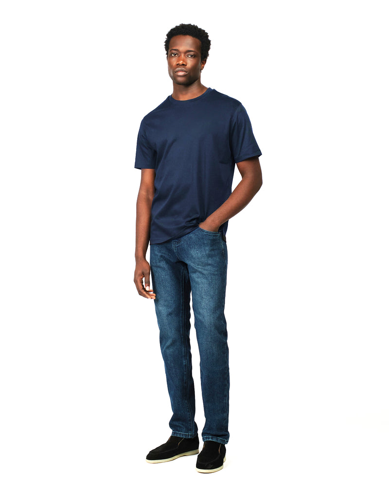 Man wearing a navy t-shirt and blue jeans on a white background