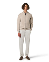 Man wearing a beige zip-up sweater and white pants