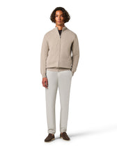 Man wearing a beige zip-up sweater and white pants 