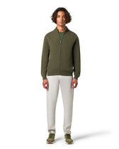 Man wearing a green zip-up hoodie and white pants
