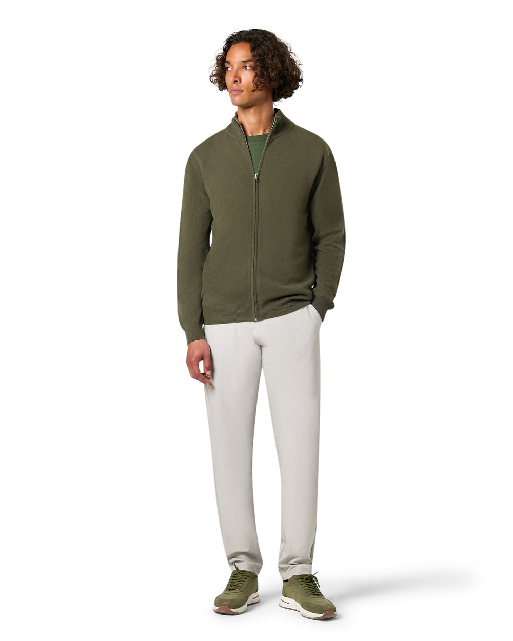 Man wearing a green zip-up hoodie and white pants 