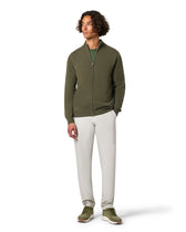 Man wearing a green zip-up hoodie and white pants 