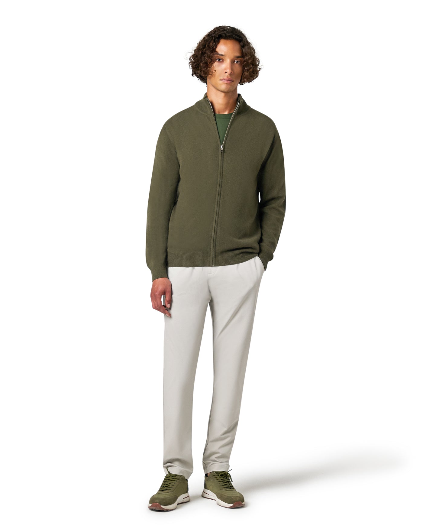 Man wearing a green zip-up sweater and light gray pants