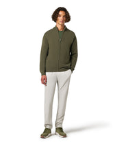 Man wearing a green zip-up sweater and light gray pants