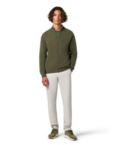 Man wearing a green zip-up hoodie and white pants