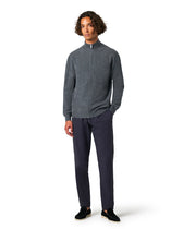 Man wearing a gray zip-up sweater and dark pants