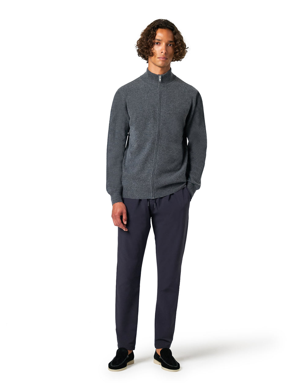 Man wearing a gray zip-up sweater and dark pants
