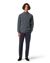Man wearing a gray zip-up sweater and dark pants