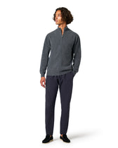 Man wearing a gray zip-up sweater and dark pants 