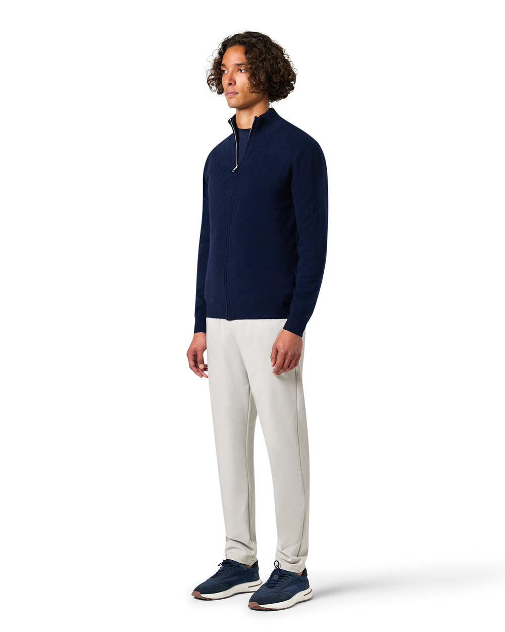 Man wearing a navy sweater and white pants 