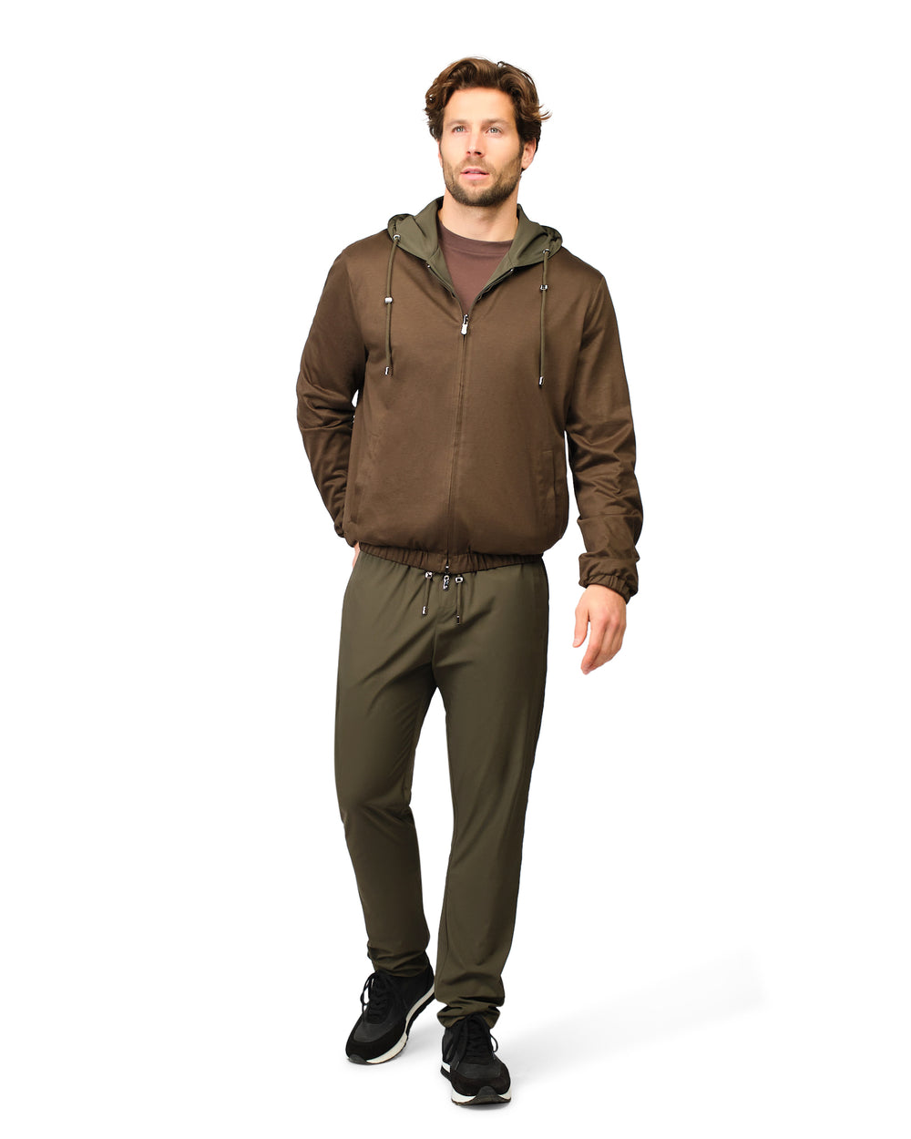 Man wearing a brown jacket and green pants on a white background