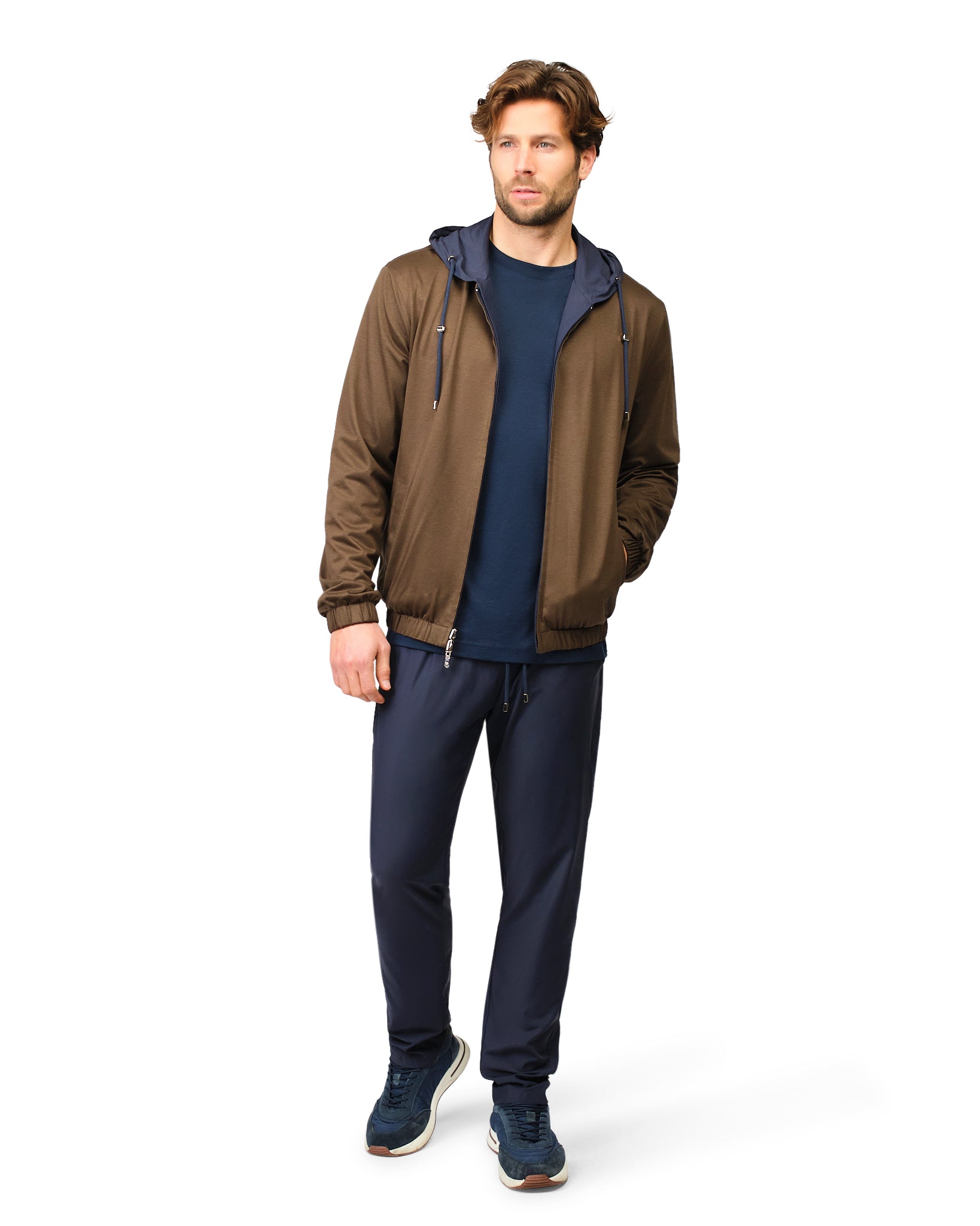 Man wearing a brown jacket and navy pants on a white background