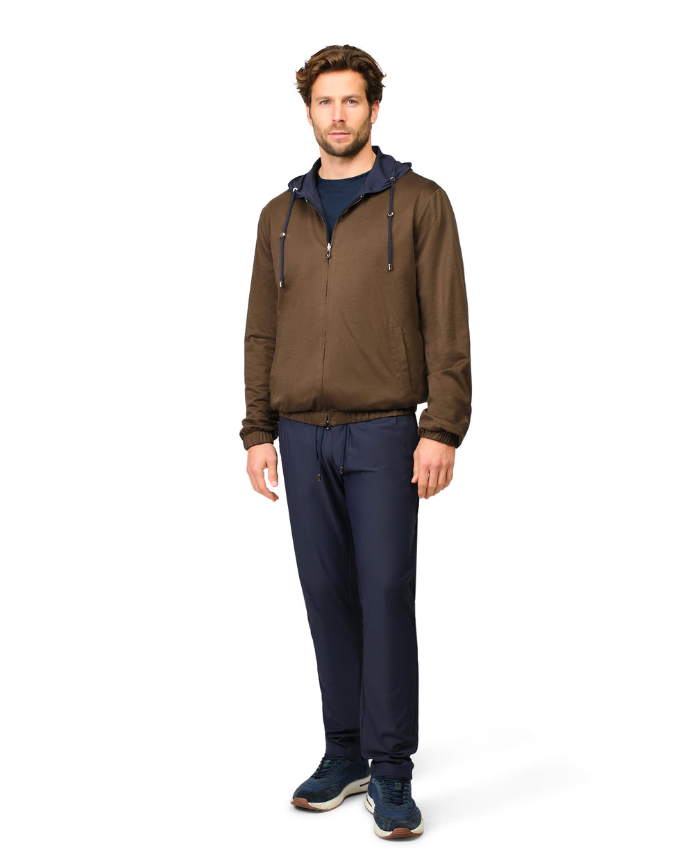 Man wearing a brown jacket and navy pants on a white background