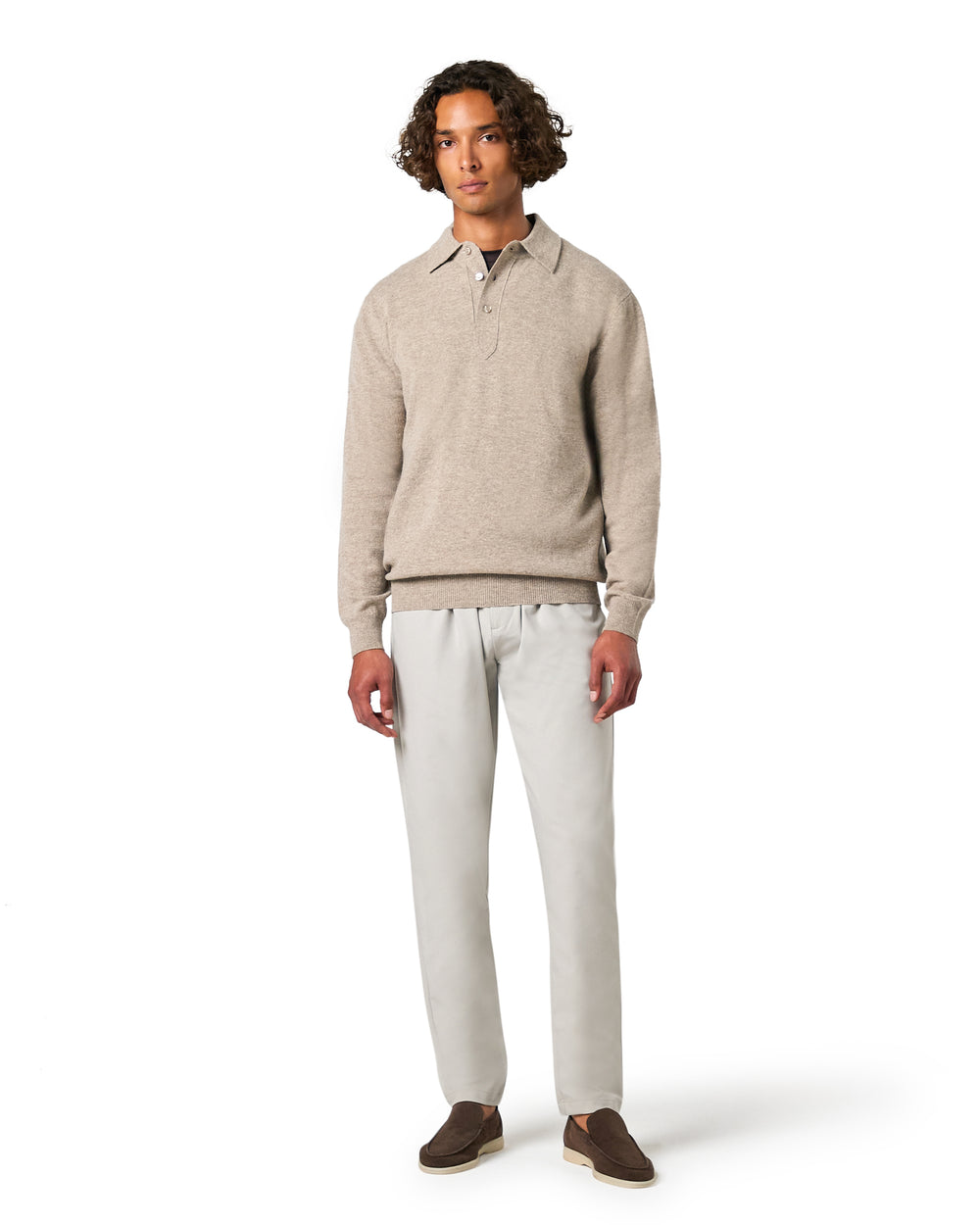 Man wearing a beige sweater and white pants