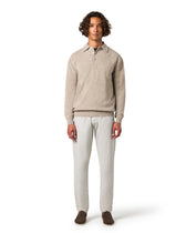 Man wearing a beige sweater and light gray pants 