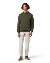 Man wearing a green long-sleeve shirt and white pants 