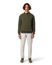 Man wearing an olive green pullover and white pants 