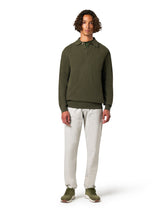 Man wearing a green long-sleeve shirt and white pants 
