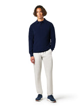 Man wearing a navy long-sleeve shirt and white pants on a white background