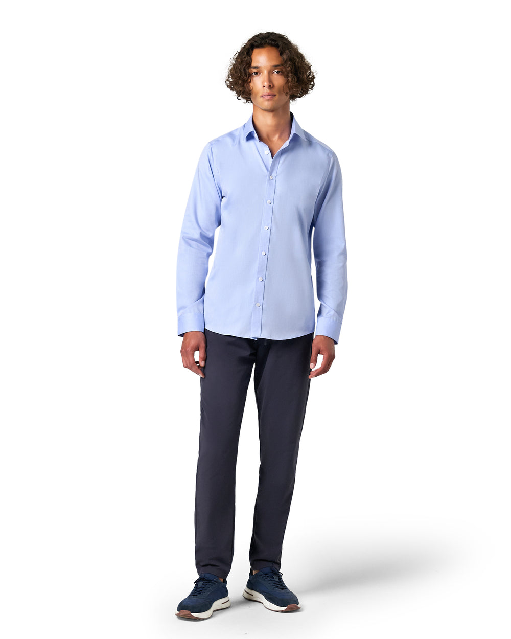 Man wearing a light blue button-up shirt and dark pants